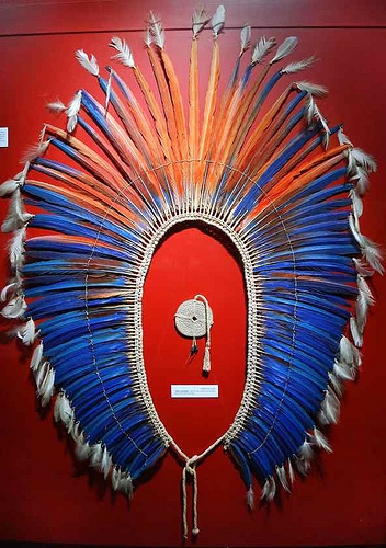 Toucado indígena com penas vermelhas e azuis