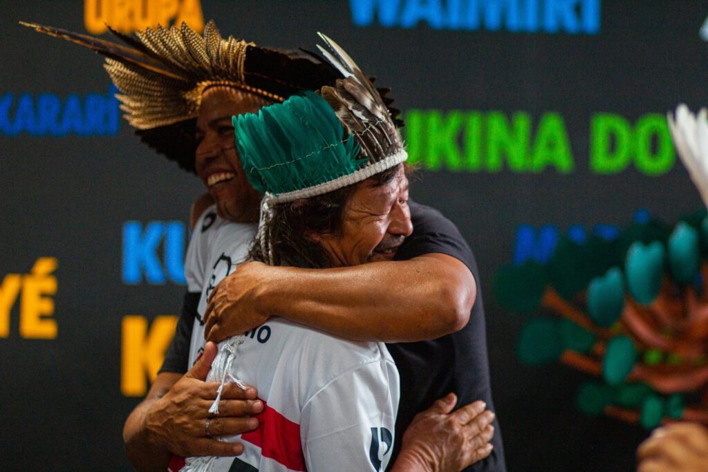 Dois indígenas homens se abraçando